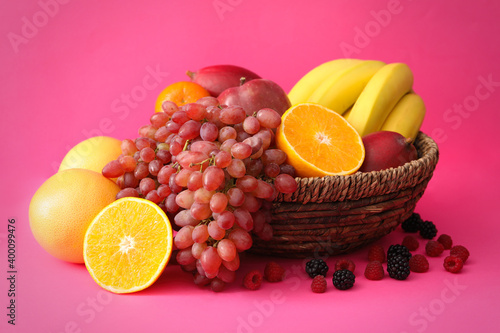 Assortment of fresh exotic fruits and berries on pink background