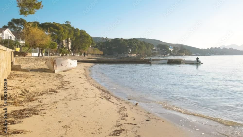 Mediterranean sunset in mallorca with beauty sea, boat in the sand with a woman walking with her dog at balearic islands Mediterranean sunset in mallorca with beauty sea, boat in the sand with a woman walking with her dog at balearic islands