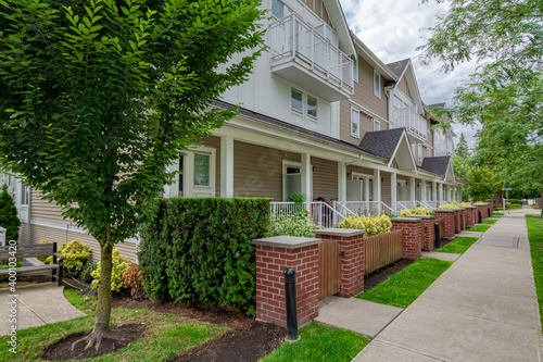 Row of townhouses with concrete pathway in front on couldy day in Vancouver, BC photo