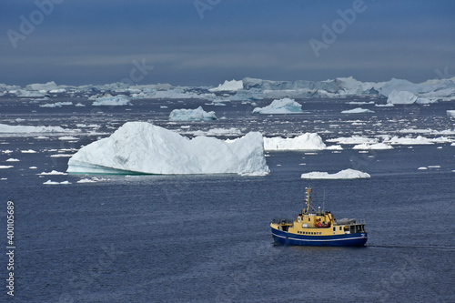 Fishing boat among icebergs in Disko Bay, Ilulissat, West Greenland photo