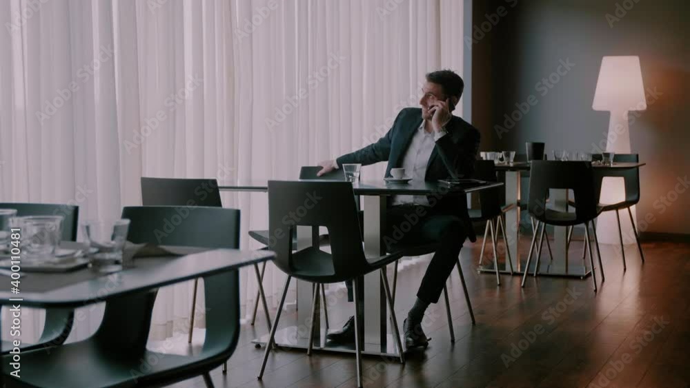 Businessman looking around the room and smiling while having a conversation on the phone Businessman looking around the room and smiling while having a conversation on the phone