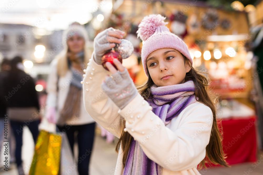 Happy teenage girl demonstrating christmas balls at street christmas market