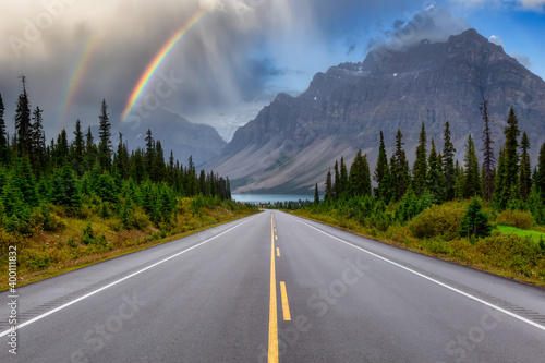 Scenic Road in the Canadian Rockies. Vibrant sunny summer day with Rainbow and Rainy Sky Composite. Taken in Icefields Parkway, Banff National Park, Alberta, Canada. © edb3_16