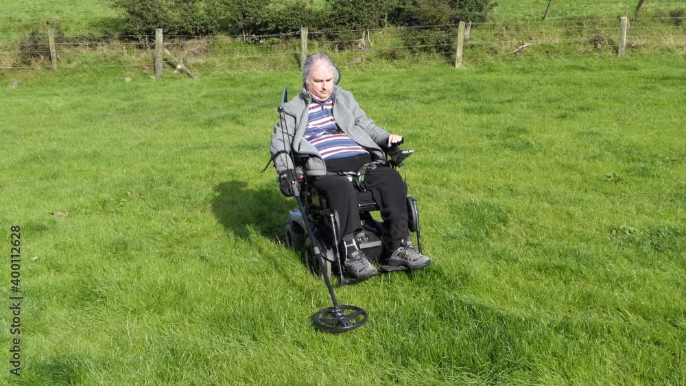 Disabled Wheelchair user metal detecting in a field Disabled Wheelchair user metal detecting in a field