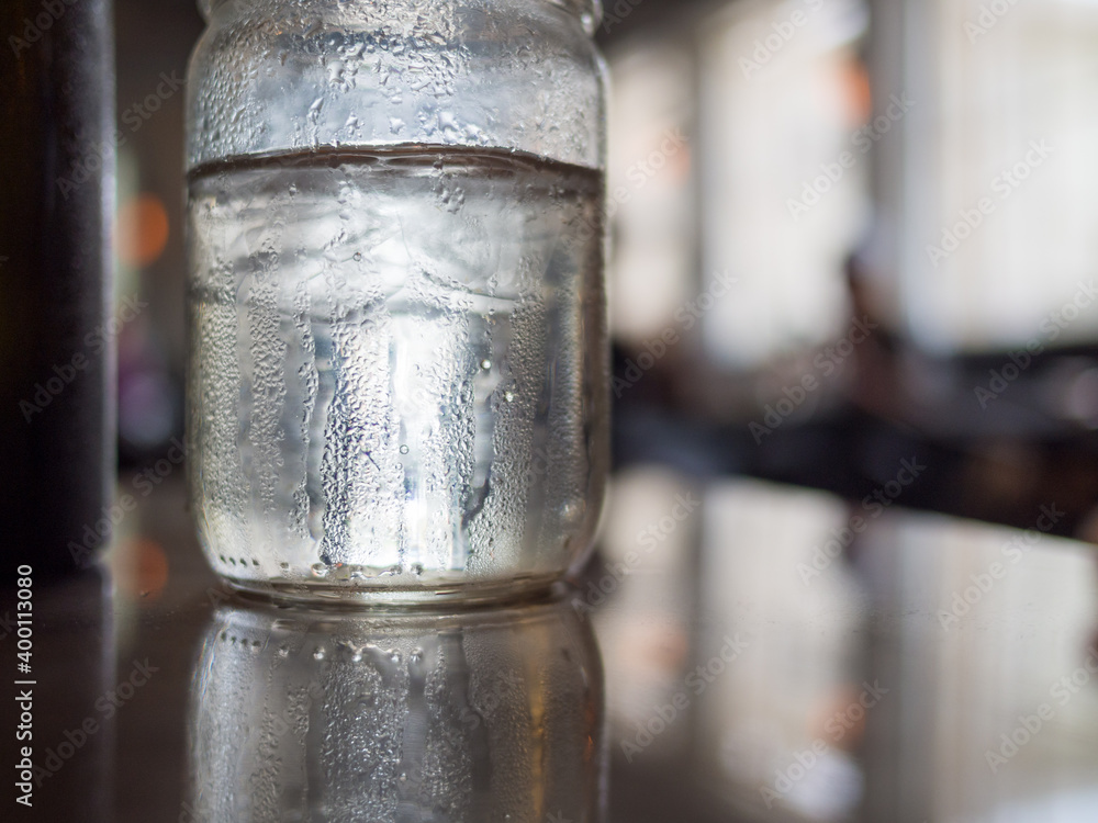 Glass of ice water on table with bokeh and reflections Glass of ice water on table with bokeh and reflections