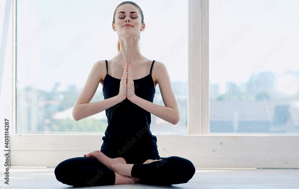 Woman practices yoga indoors near the window meditation relax crossed legs