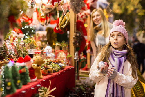 Surprised teenage girl looking at tree decorations at street christmas market © JackF