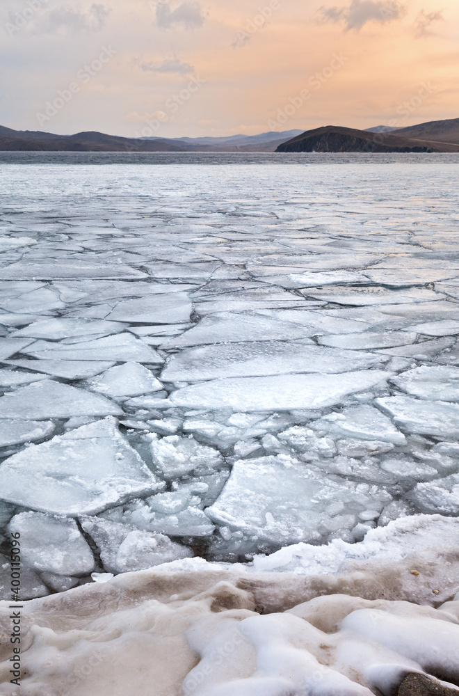 Baikal Lake in December morning. Freeze-up in the Olkhon Gate Strait, floating ice floes near the coast and open water in the strait. Beautiful winter landscape. Natural background