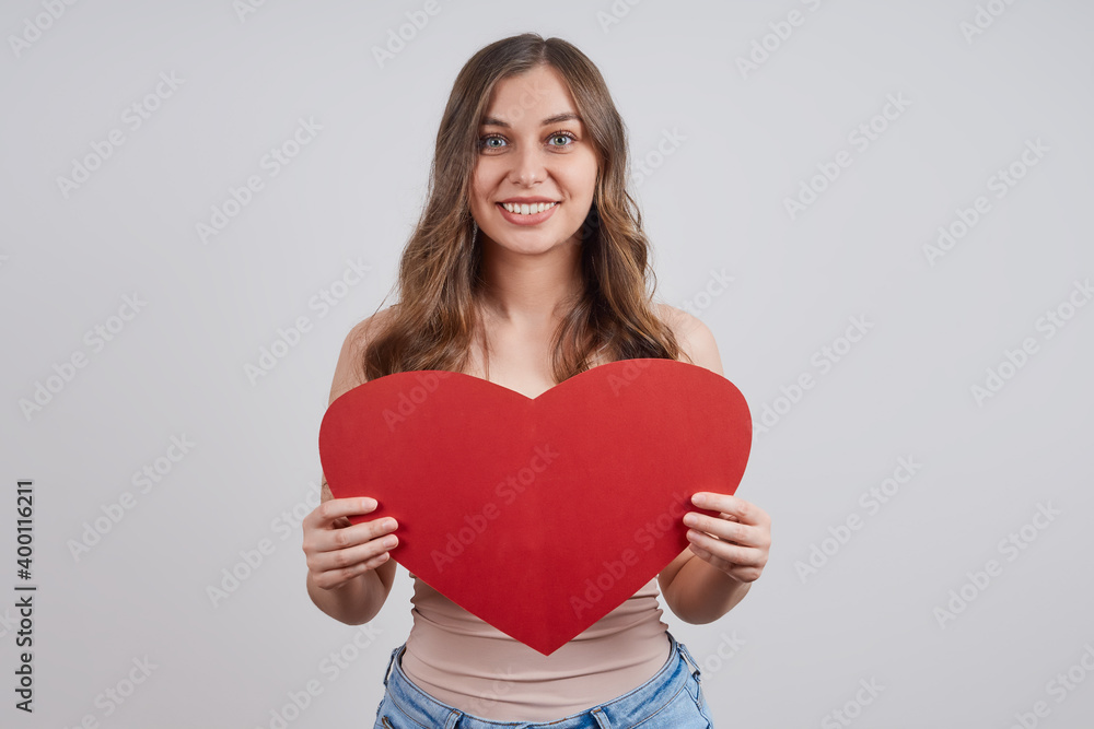 Cute, happy woman with a paper heart, looking at the camera, smiling. Happy Valentine's Day. Cute, happy woman with a paper heart, looking at the camera, smiling. Happy Valentine's Day.