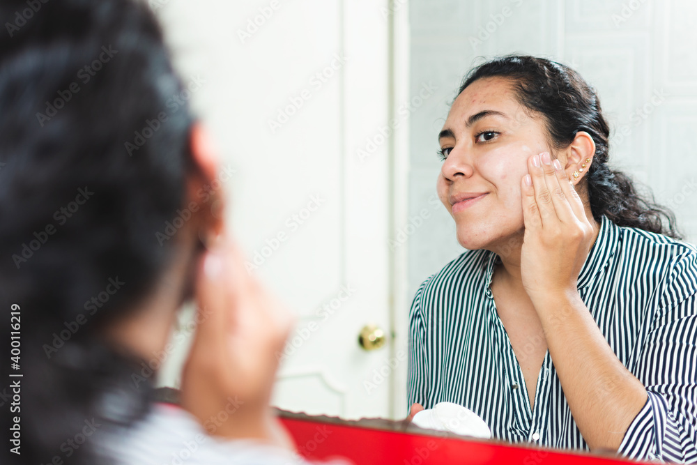 A woman putting on cream on her face