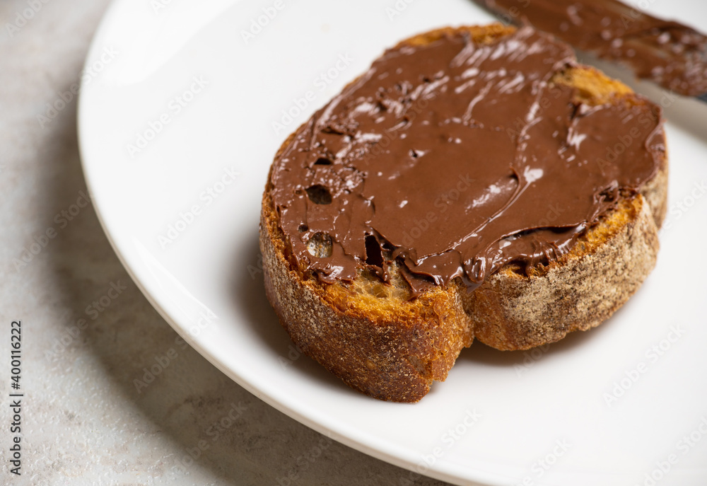 Slice of homemade bread with chocolate cream on the kitchen table for breakfast. Selective focus. Shallow depth of field.
