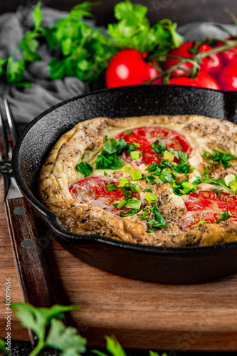  Homemade omelet with tomatoes and herbs in a pan on the table close up vertical photo