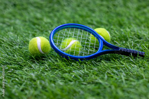 Tennis racket with tennis ball on green grass