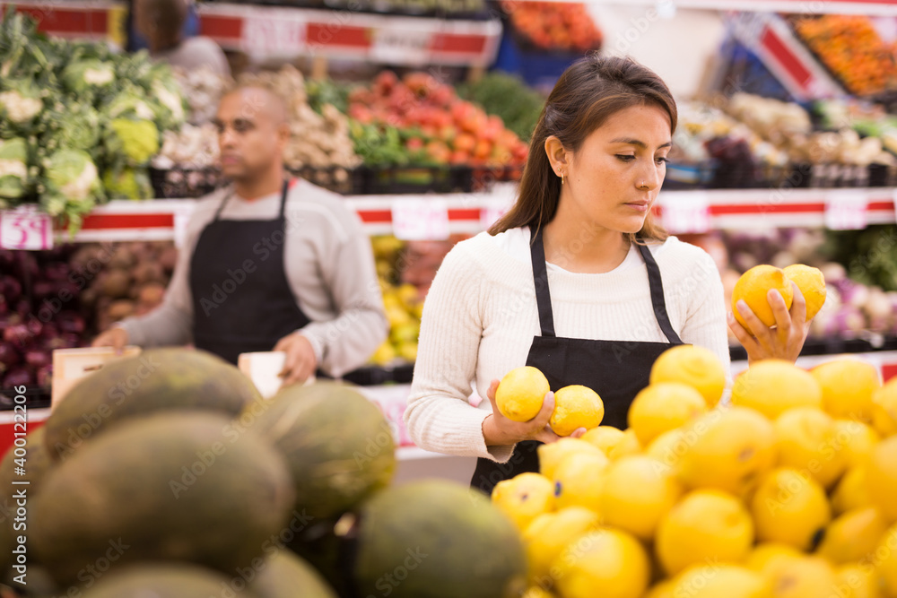 Merchandiser lays out ripe lemons on the shelves in the supermarket