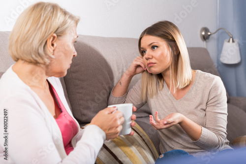 Adult daughter and her mother discussing something at home..