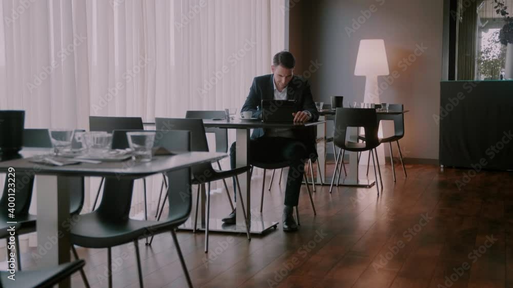 Businessman sitting in an empty restaurant and typing on his tablet Businessman sitting in an empty restaurant and typing on his tablet