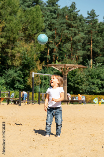 little girl in a white t-shirt with a blue ball on the beach.child throws the ball © Елена Гурова