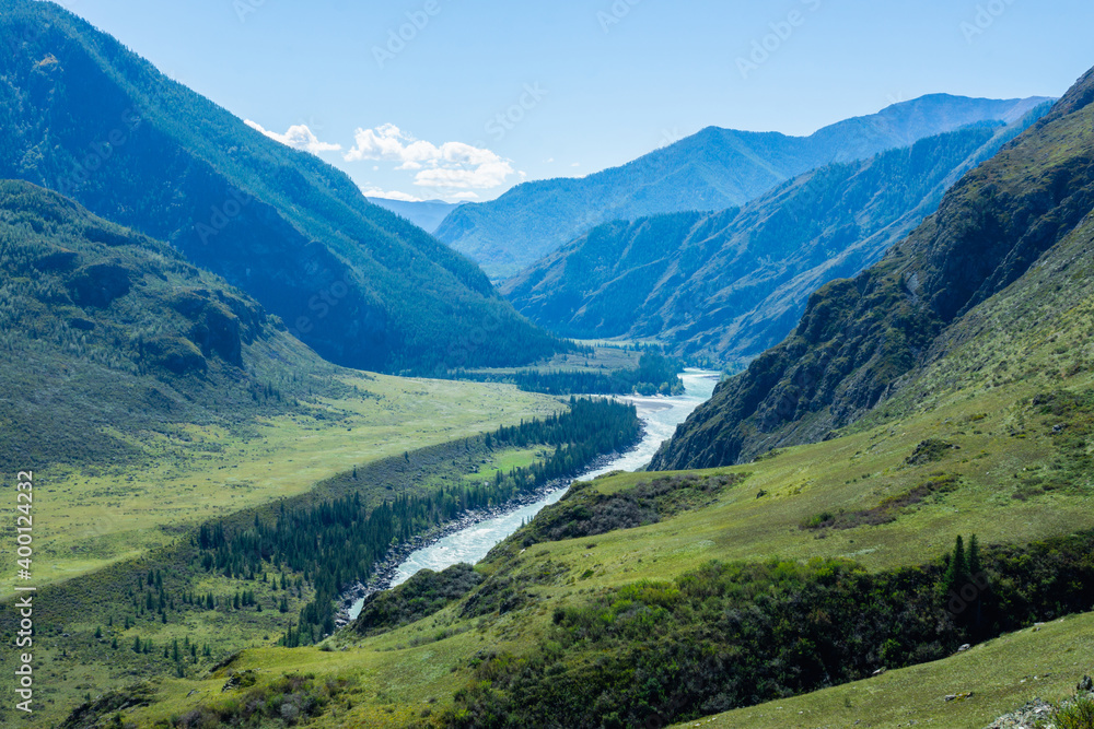 Fototapeta premium Green valley landscape and small river with mountains on background