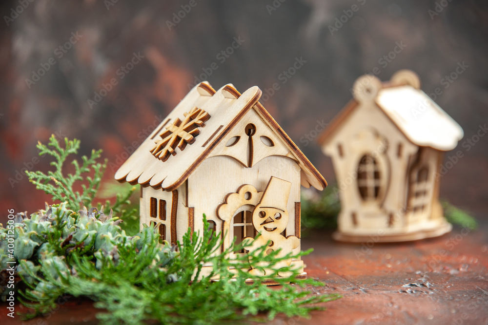front view wooden toy house pine tree branches on dark isolated background