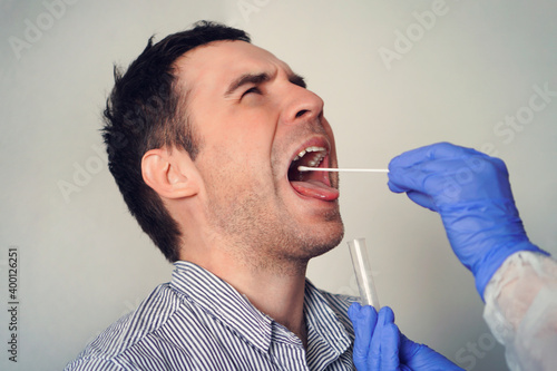 Doctor Doing Coronavirus Test For male Patient. DNA test. Collection of mucus from the throat for research in the laboratory. Taking a saliva sample from a man. PCR polymerase chain reaction