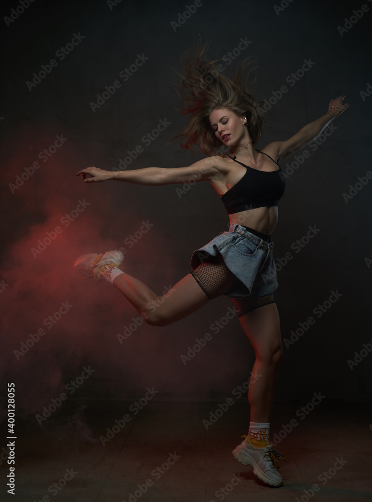Caucasian beautiful woman with long brown hairs jumps dancing in dark smokey background.