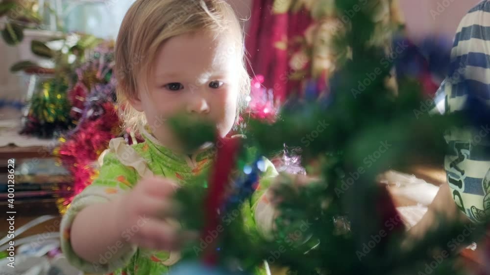 Family decorates Christmas tree. Toddler girl decorates Christmas pine tree with her grandmother. Family decorates Christmas tree. Toddler girl decorates Christmas pine tree with her grandmother.