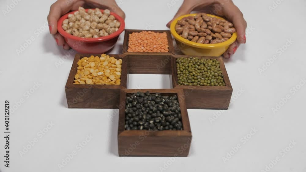 Various colorful raw dal/lentils kept in separate places against a white background. Whole black gram/Sabut Urad  Moong(green)  Masoor(red)  Arhar(yellow) lentils with chickpea/Chana  and kidney be...