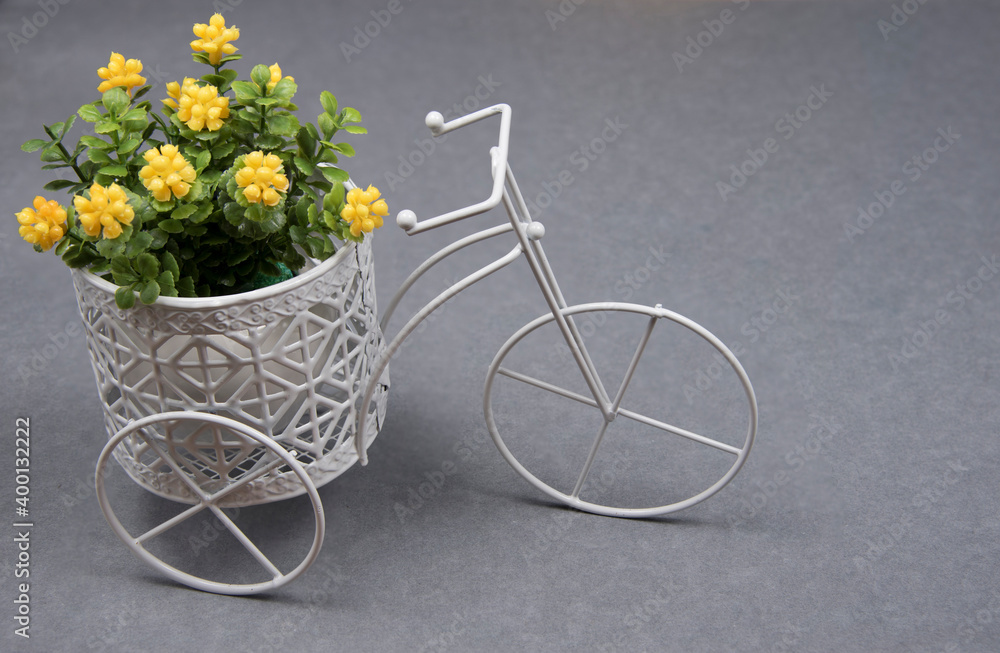 Artificial plastic flowers on white bike on gray background. Colors of year 2021 gray and illuminating yellow.