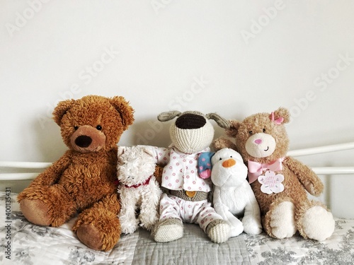 Assorted cuddly toys or teddy bears sitting on a cosy bed in a row