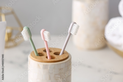 Holder with toothbrushes on table in bathroom