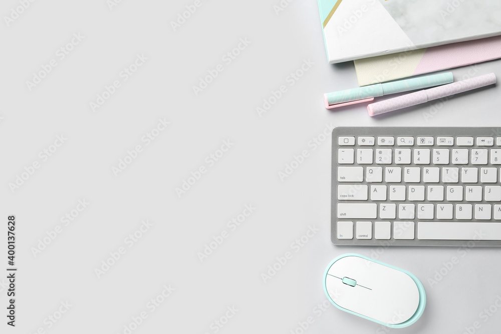 Computer keyboard, mouse and stationery on light background
