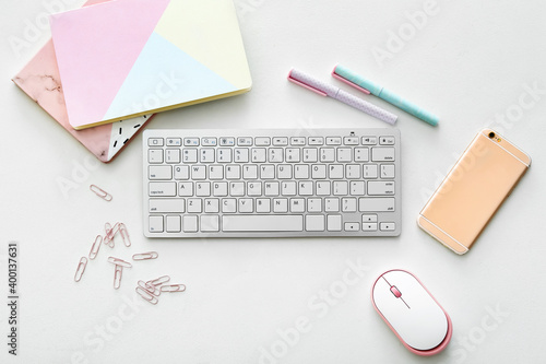 Computer keyboard with mouse, stationery and mobile phone on white background