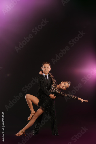 Cute little children dancing against dark background