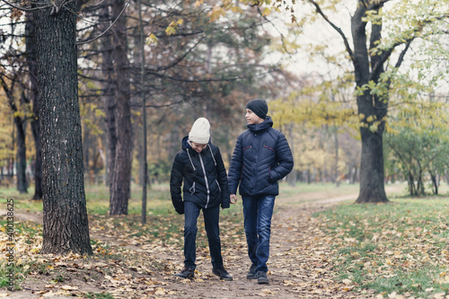 teen girl and boy walking through the park and enjoys autumn, beautiful nature with yellow leaves © soleg