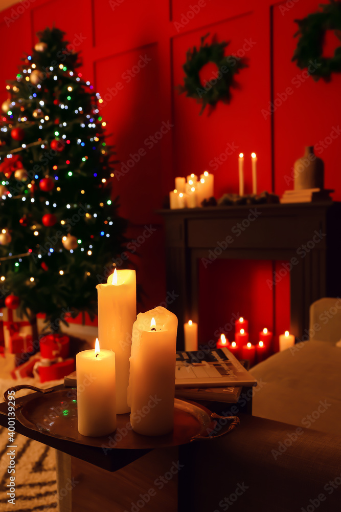 Burning candles in living room decorated for Christmas