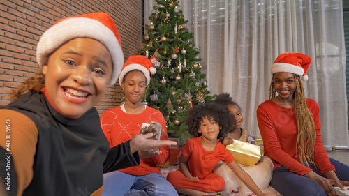 African American black family, women and kid girl daughters sharing gifts on Merry Christmas Eve Xmas Party. They talking video call conferece online. Celebration together at home. People lifestyle. photo