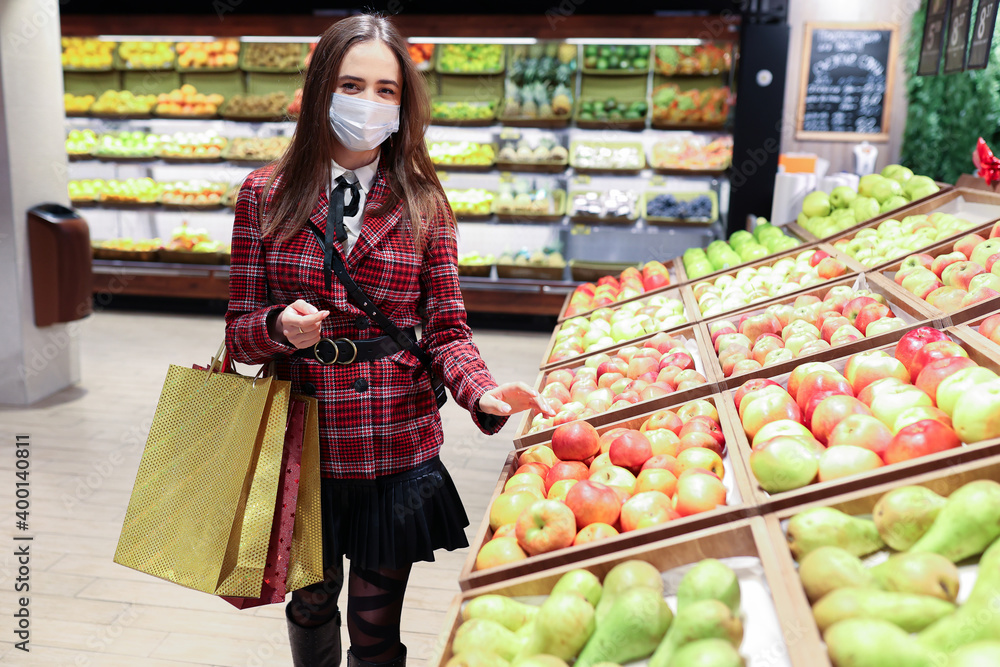 A young woman in a protective mask chooses fruit in the store A young woman in a protective mask chooses fruit in the store
