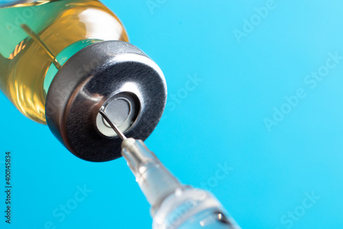 Macro photo needle syringe and medical antibiotic medicine on a blue background. The concept of vaccination in health care, the vaccine against coronavirus covid.