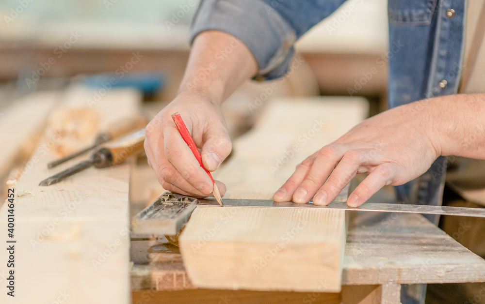 Close up man's hands taking measurement of a wooden plank Close up man's hands taking measurement of a wooden plank