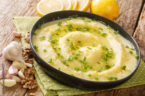 Delicious Greek Skordalia made from mashed potatoes with garlic, lemon, nuts and olive oil close-up in a plate on the table. horizontal photo