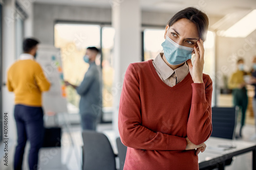 Distraught businesswoman wearing face mask while working in the office during coronavirus pandemic.