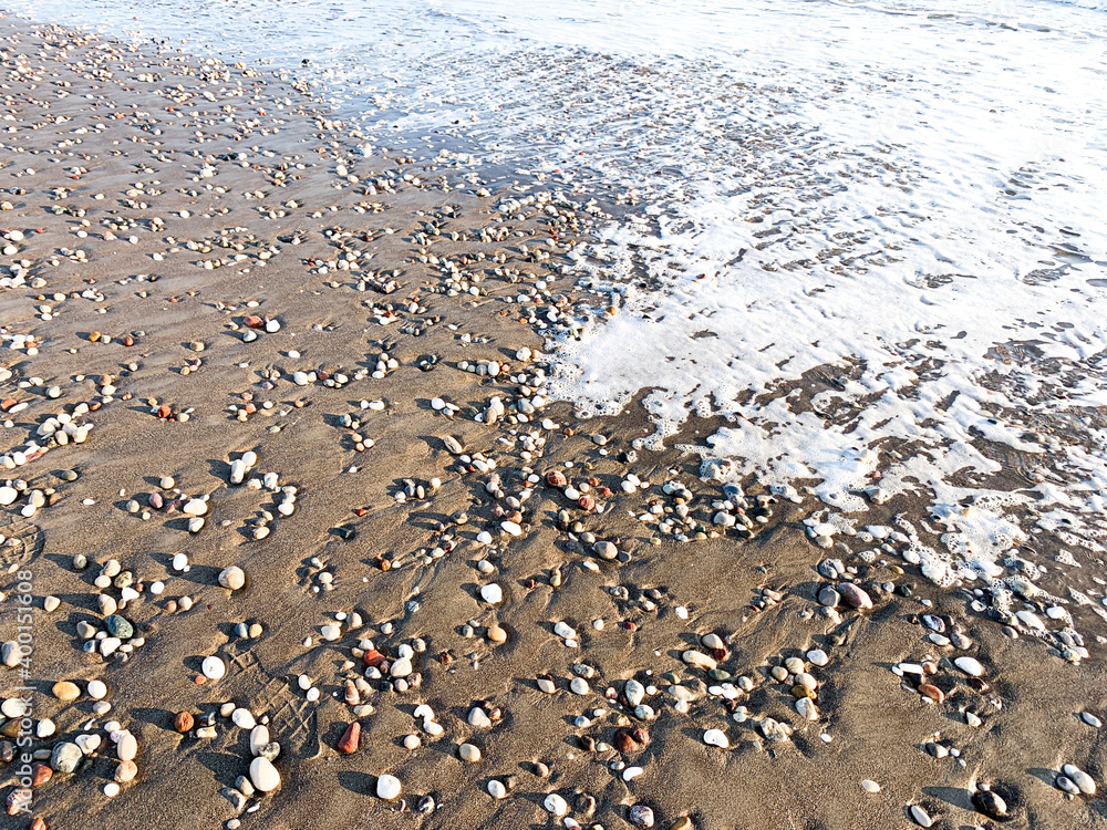 Sea water running on the sandy coastline with pebbles Sea water running on the sandy coastline with pebbles