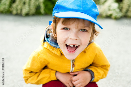 A cheerful child in a blue cap laughs merrily. © Anna