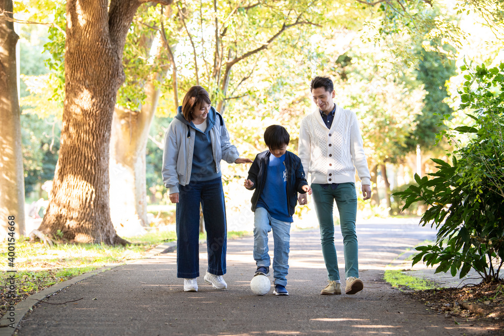若い親子と夫婦が仲良く公園で散歩をしている