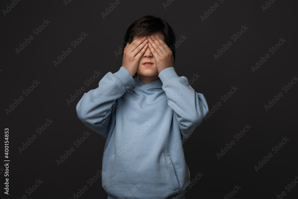 Portrait of boy 10-12 years old covering his eyes with hands. Facial expression concept. Studio shot, white background Portrait of boy 10-12 years old covering his eyes with hands. Facial expression concept. Studio shot, white background