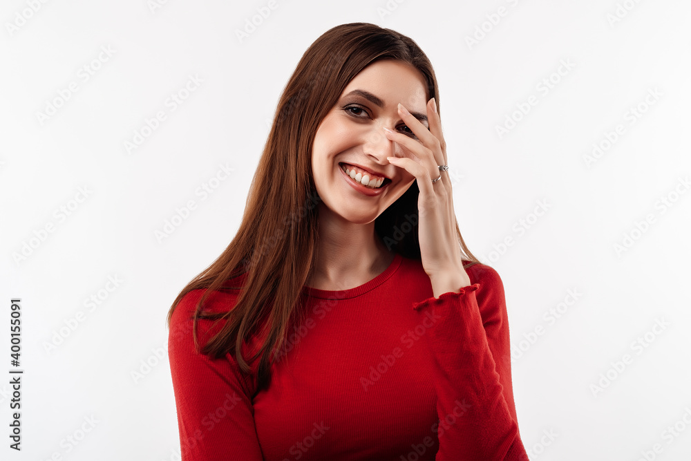 Portrait of embarrassed young woman with long chestnut hair in casual red sweater looking at camera Portrait of embarrassed young woman with long chestnut hair in casual red sweater looking at camera