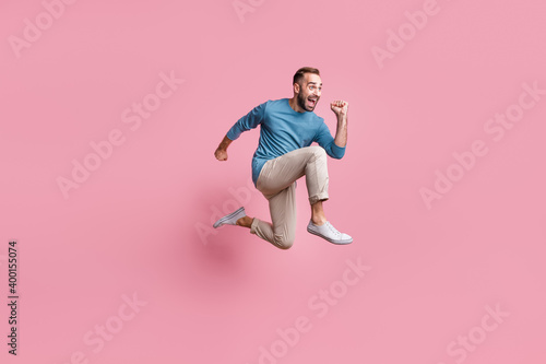 Full length photo of hurry funky young guy wear blue pullover jumping running fast isolated pink color background