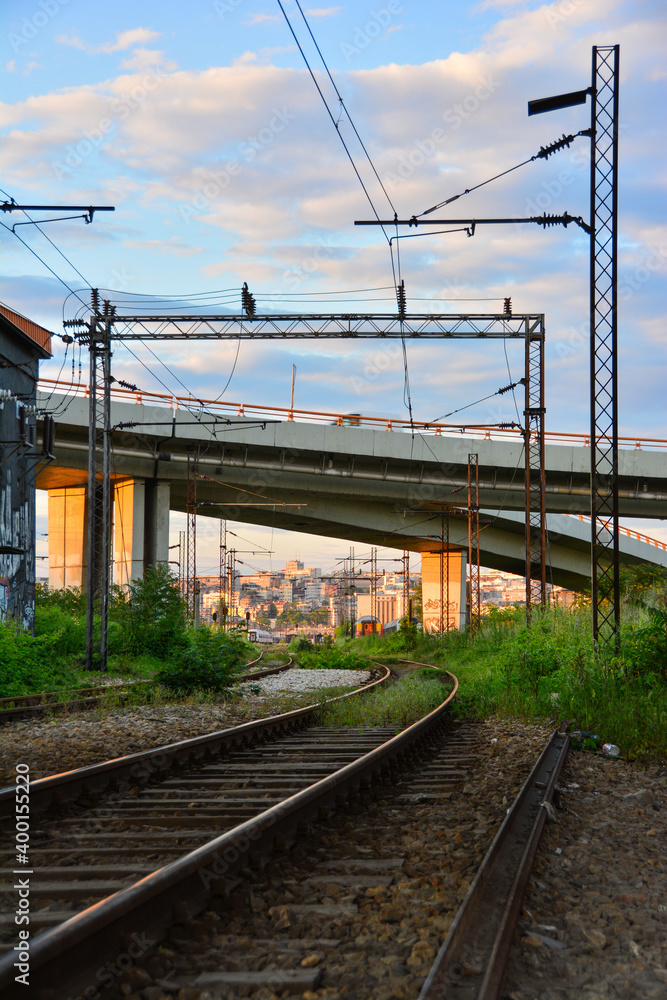 Scenic view of an abandoned railway line under the highway overgrown with vegetation in Belgrade, Serbia. Colorful view of railroad at sunset. Scenic view of an abandoned railway line under the highway overgrown with vegetation in Belgrade, Serbia. Colorful view of railroad at sunset.
