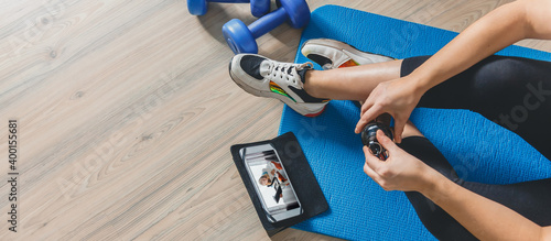 Fitness at home, remote training with virtual instructor. Woman in sportswear sitting on the floor with dumbbells laptop at home. Sports and recreation concept in lockdown with fitness apps online photo