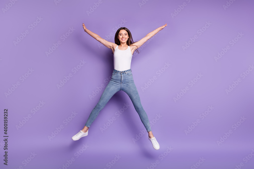 Full size photo of beautiful cheerful girl jump up rejoice star shape wear white tank-top isolated on purple color background